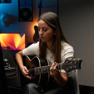 Singer-songwriter recording with an acoustic guitar in a studio